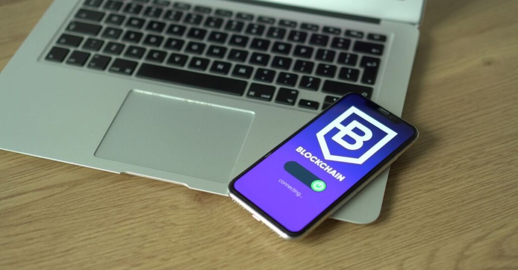 Smartphone displaying blockchain application resting on a laptop, symbolizing modern technology and finance.