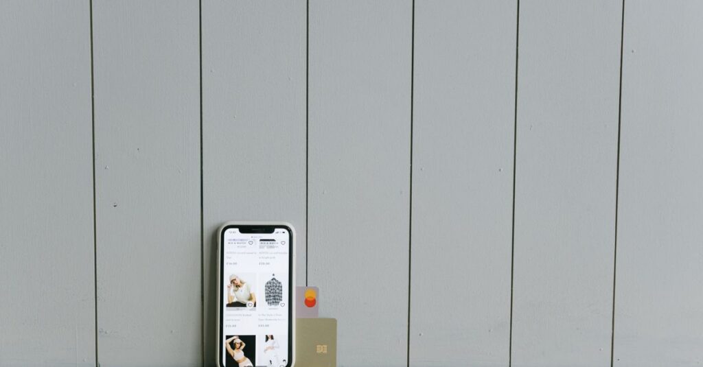 A smartphone displaying an ecommerce site with a credit card, set on a wooden surface, depicting online shopping.